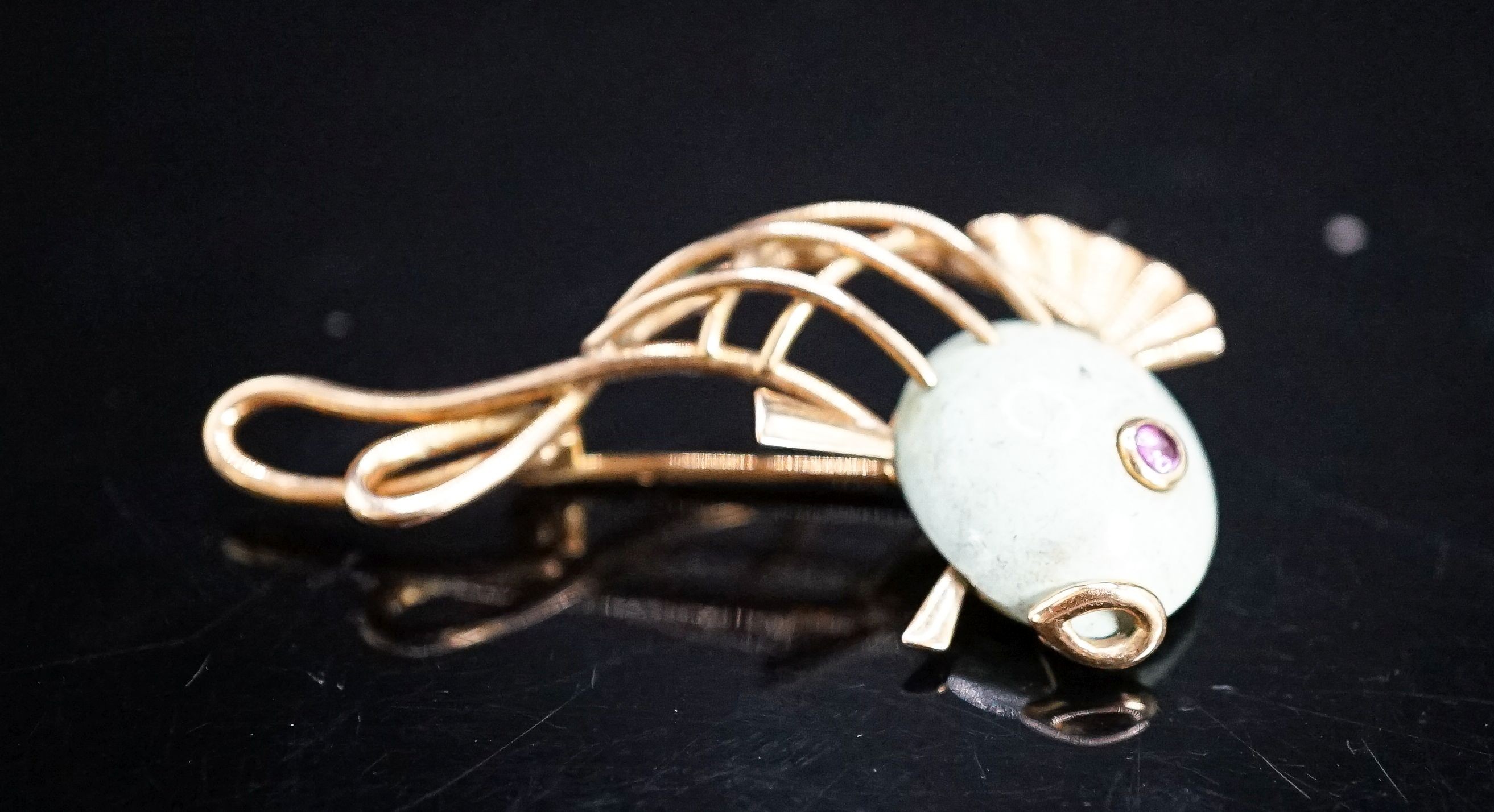 A Viennese 585 yellow metal, hardstone and cabochon ruby set brooch, modelled as a stylised fish, 39mm, gross weight 5.4 grams.
